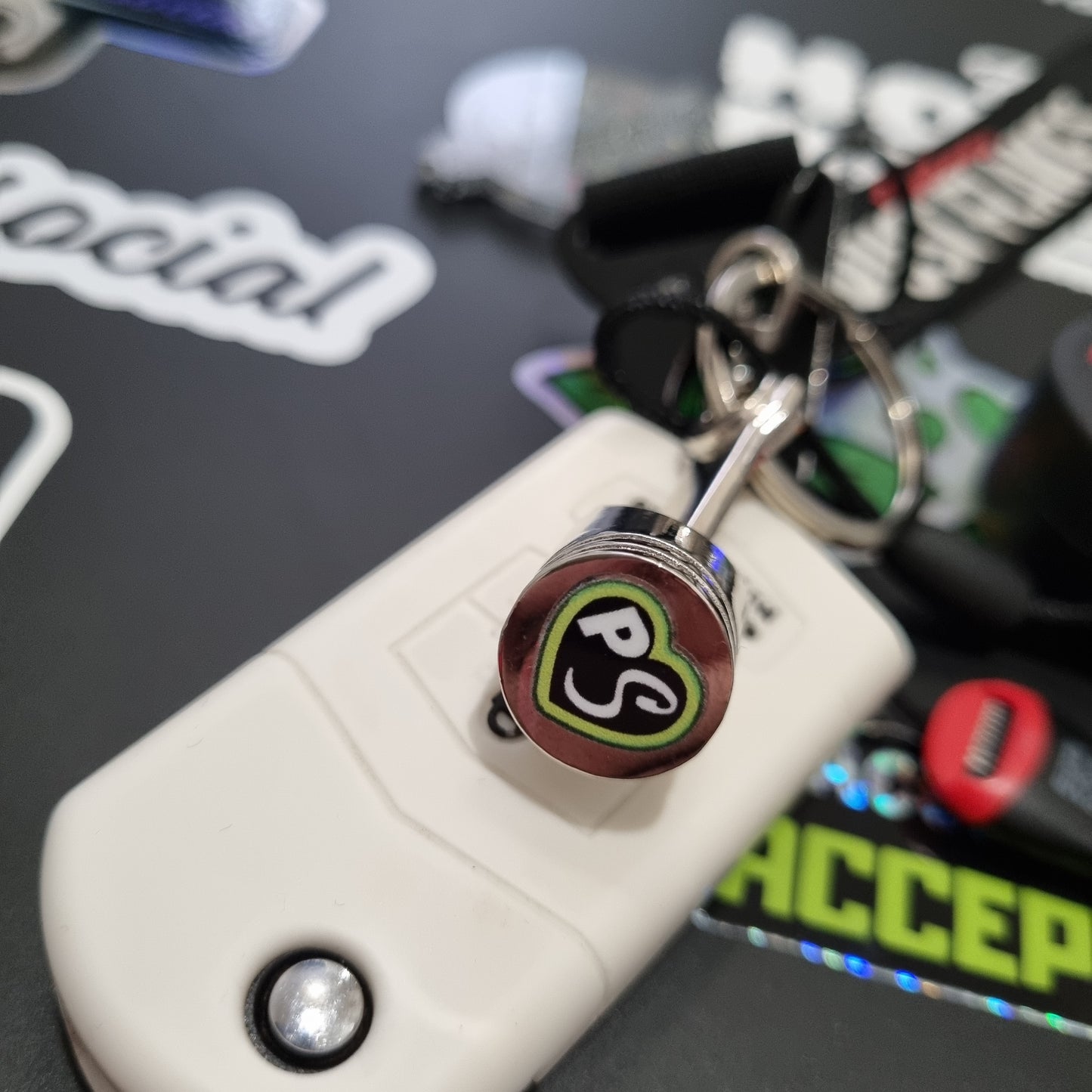 PITSTOP.Social branded solid metal piston key chain fidget toy with car keys, top down view over car keys