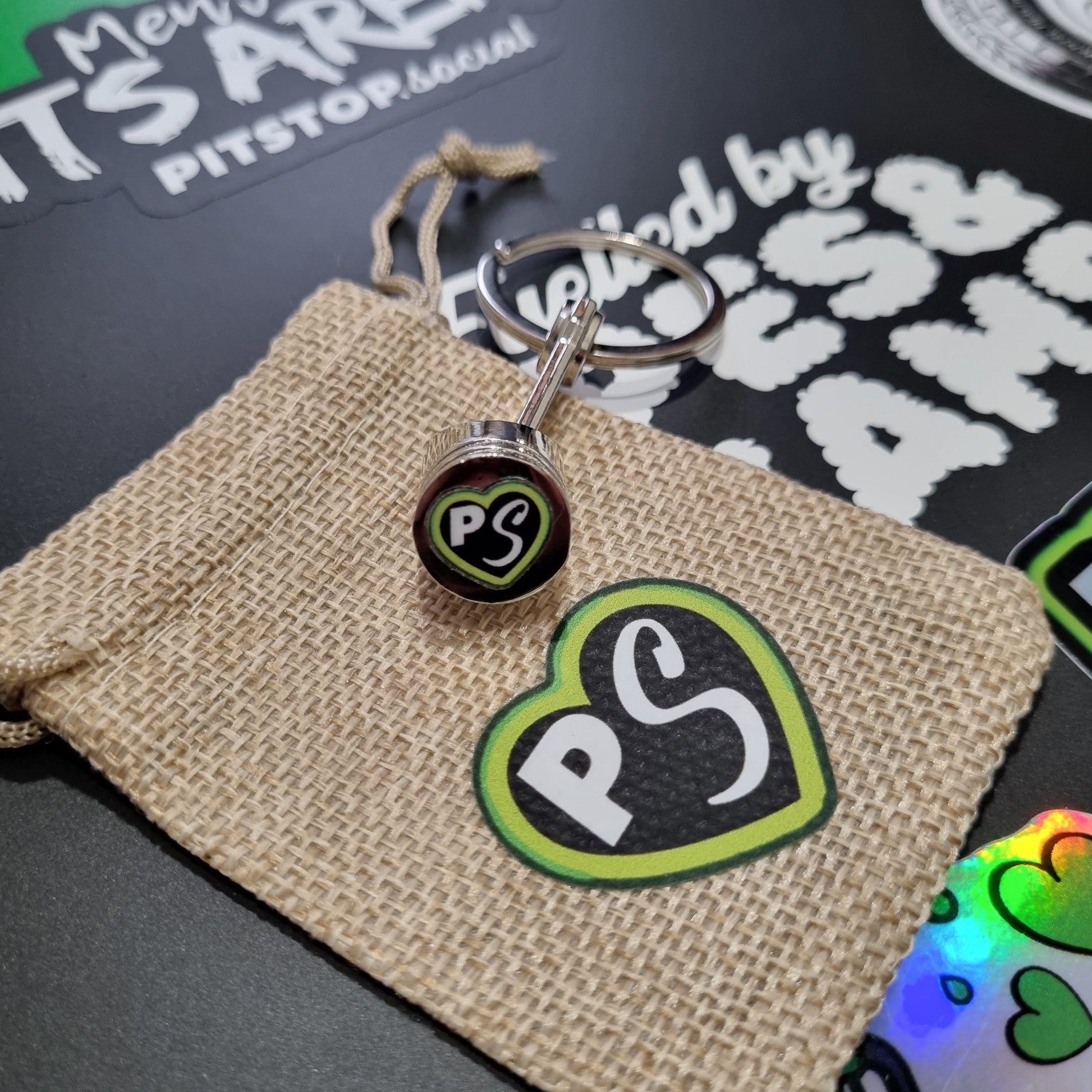 Natural gift bag with PITSTOP.Social logo and green heart on a solid metal piston key chain fidget 