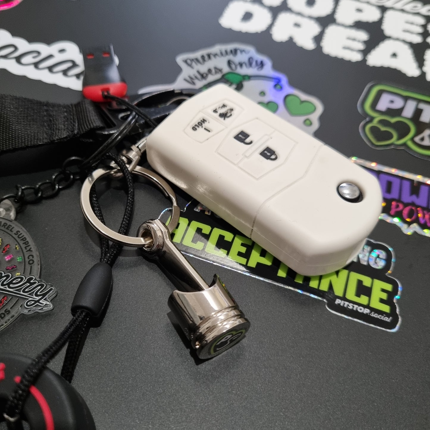 PITSTOP.Social branded solid metal piston key chain fidget toy with MX5 car keys on  a sticker bombed background