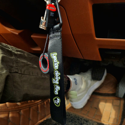 A black key tag with the text 'SLOW DOWN You're Doing Fine' in bold lettering, attached to a metal keychain ring inside Option Pack MAZDA MX5