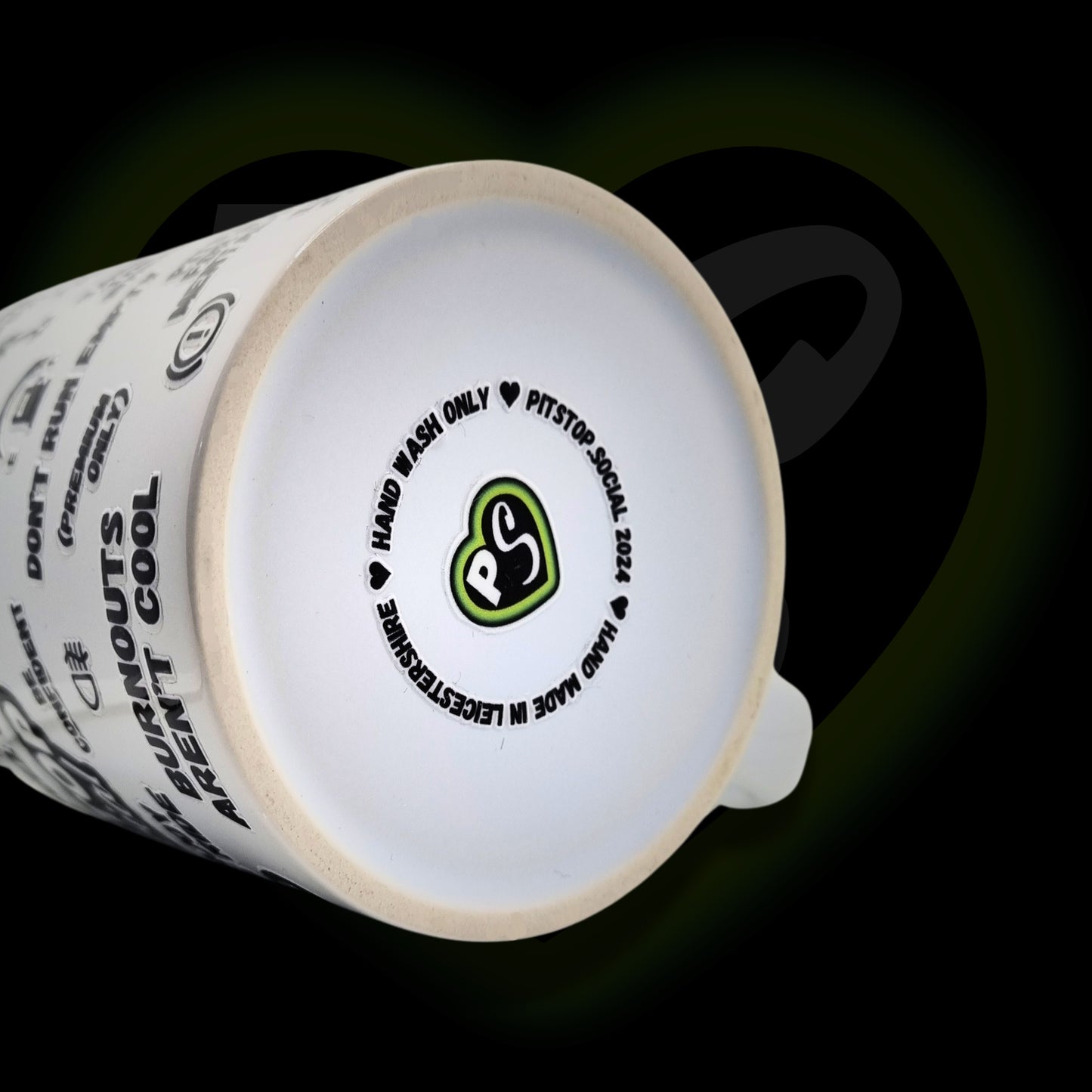A white ceramic mug with 3D raised text and graphics including the Pitstop Social logo, various symbols, and care instructions at base, made in Leicestershire